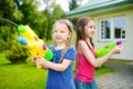 Adorable little girls playing with water guns on hot summer day. Cute children having fun with water outdoors. Royalty Free Stock Photo