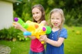 Adorable little girls playing with water guns on hot summer day. Cute children having fun with water outdoors. Royalty Free Stock Photo