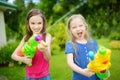 Adorable little girls playing with water guns on hot summer day. Cute children having fun with water outdoors. Royalty Free Stock Photo