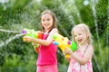 Adorable little girls playing with water guns on hot summer day. Cute children having fun with water outdoors. Royalty Free Stock Photo