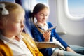 Adorable little girls traveling by an airplane. Children sitting by aircraft window and playing with toy plane. Traveling with kid Royalty Free Stock Photo