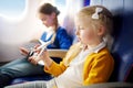 Adorable little girls traveling by an airplane. Children sitting by aircraft window and playing with toy plane.