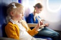 Adorable little girls traveling by an airplane. Children sitting by aircraft window and playing with toy plane. Traveling with kid Royalty Free Stock Photo