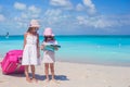 Adorable little girls walking big suitcase and map searching the way on tropical beach