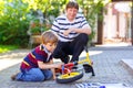 Adorable little kid boy and father repair chain on bikes and change wheel of balance bicycle. Family, dad and son work Royalty Free Stock Photo