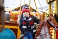 Adorable little kid boy riding on a carousel horse at Christmas funfair or market, outdoors. Royalty Free Stock Photo