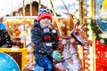 Adorable little kid boy riding on a merry go round carousel horse at Christmas funfair or market, outdoors. Happy child Royalty Free Stock Photo