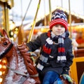 Adorable little kid boy riding on a merry go round carousel horse at Christmas funfair or market, outdoors. Happy child Royalty Free Stock Photo