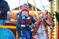 Adorable little kid boy riding on a merry go round carousel horse at Christmas funfair or market, outdoors. Happy child Royalty Free Stock Photo