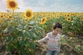 Adorable little kid boy on summer sunflower field outdoor. Happy child sniffing a sunflower flower on green field Royalty Free Stock Photo