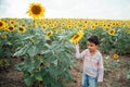 Adorable little kid boy on summer sunflower field outdoor. Happy child sniffing a sunflower flower on green field. Royalty Free Stock Photo