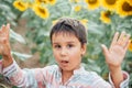 Adorable little kid boy on summer sunflower field outdoor. Happy child sniffing a sunflower flower on green field. Royalty Free Stock Photo