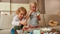 Adorable little kids painting colorful Easter eggs together, sitting on a couch while spending time at home Royalty Free Stock Photo