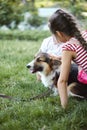 Adorable little kids petting and playing with Welsh Corgi dog on the grass in the park.