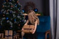 adorable little preschool blonde girl in a black dress holding new years present near a christmas tree. dark loft room Royalty Free Stock Photo