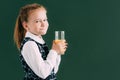 adorable little schoolgirl holding glass of orange juice and smiling