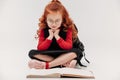 adorable little schoolgirl reading book on floor Royalty Free Stock Photo