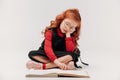 adorable little schoolgirl reading book while sitting on floor Royalty Free Stock Photo