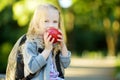 Adorable little schoolgirl studying outdoors on bright autumn day. Young student doing her homework. Education for small kids. Royalty Free Stock Photo