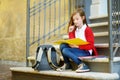 Adorable little schoolgirl studying outdoors on bright autumn day. Young student doing her homework. Education for small kids. Royalty Free Stock Photo