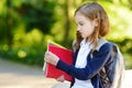 Adorable little schoolgirl studying outdoors on bright autumn day. Young student doing her homework. Education for small kids. Royalty Free Stock Photo