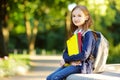 Adorable little schoolgirl studying outdoors on bright autumn day. Young student doing her homework. Education for small kids. Royalty Free Stock Photo