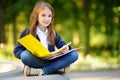 Adorable little schoolgirl studying outdoors on bright autumn day. Young student doing her homework. Education for small kids. Royalty Free Stock Photo