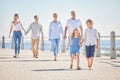 Adorable little sibling brother and sister holding hands while walking ahead on a seaside promenade while their parents Royalty Free Stock Photo