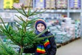 Adorable little smiling kid boy holding Christmas tree on market. Happy healthy child in winter fashion clothes choosing Royalty Free Stock Photo