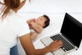 Adorable little sweet newborn baby girl lying on white bed near her mom using notebook laptop computer, cute infant with her busy Royalty Free Stock Photo