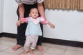 Adorable little toddler baby girl child taking first steps with father`s help indoor at home, in real life interior