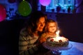 Adorable little toddler girl celebrating second birthday. Baby child daughter and young mother blowing candles on cake Royalty Free Stock Photo