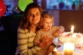 Adorable little toddler girl celebrating second birthday. Baby child daughter and young mother blowing candles on cake Royalty Free Stock Photo