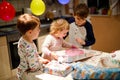 Adorable little toddler girl celebrating second birthday. Baby child and two kids boys unpacking gifts. Happy healthy