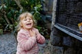 Adorable little toddler girl feeding parrots in zoological garden. Happy child playing and feed trusting friendly birds Royalty Free Stock Photo