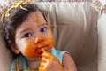 Adorable little toddler girl or infant baby eating delicious spaghetti food with tomato sauce. Funny cute infant girl get hungry