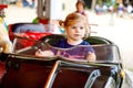 Adorable little toddler girl riding on funny car on roundabout carousel in amusement park. Happy healthy baby child Royalty Free Stock Photo