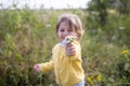 Adorable little toddler stretches a flower into the camera in a summer field on a sunny day Royalty Free Stock Photo