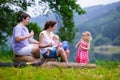 Adorable loung family with kids hiking at a lake