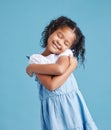 Adorable loveable little girl looking happy while hugging embracing herself. Cute kid with positive self-esteem against