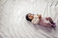 Adorable lovely Afro baby girl looking at camera while lying on comfortable bed Royalty Free Stock Photo