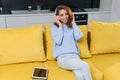 Adorable modern woman with wavy brown hair dressed in stylish casual clothes resting on the comfortable sofa in the