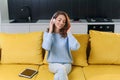 Adorable modern woman with wavy brown hair dressed in stylish casual clothes resting on the comfortable sofa in the