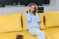 Adorable modern woman with wavy brown hair dressed in stylish casual clothes resting on the comfortable sofa in the Royalty Free Stock Photo