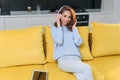 Adorable modern woman with wavy brown hair dressed in stylish casual clothes resting on the comfortable sofa in the