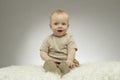 Adorable 9 month baby boy on the white blanket on grey background