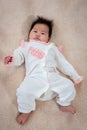 Adorable 3 month old newborn baby girl laying on the soft carpet and looking at the camera. The girl just woke up from her sleep Royalty Free Stock Photo