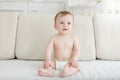 Portriat of adorable 10 months old baaby boy in diapers sitting on sofa Royalty Free Stock Photo