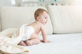 Adorable 10 months old baby boy in diapers sitting on sofa