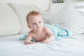 Adorable 9 months old baby boy lying on bed under big blue towel after having bath Royalty Free Stock Photo